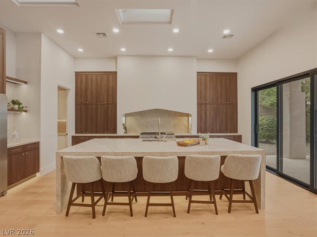 3 Isleworth Drive, Henderson, NV 89052 A well-lit kitchen with a spacious island, integrated gas range, and large sliding glass doors.