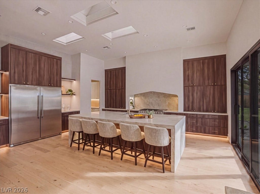 3 Isleworth Drive, Henderson, NV 89052 An inviting kitchen with a vast island and plentiful wood cabinetry awaits culinary exploration.