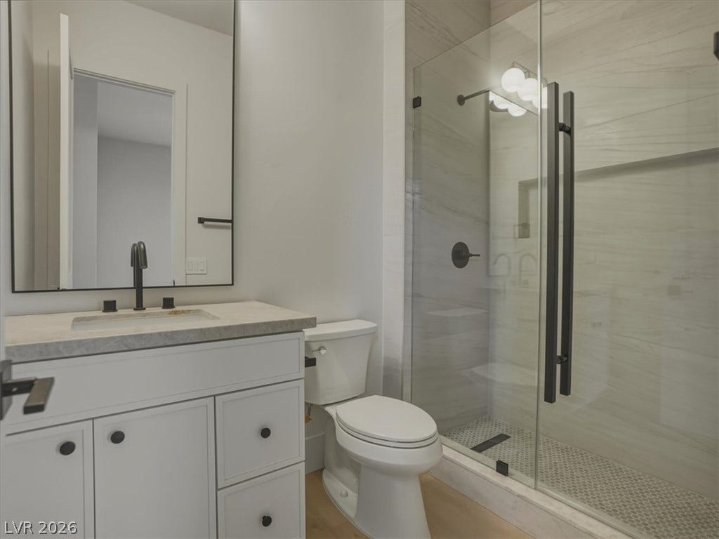 3 Isleworth Drive, Henderson, NV 89052 A refined bathroom featuring a glass-enclosed shower and a sleek vanity with an integrated sink.