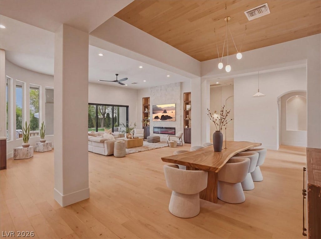 3 Isleworth Drive, Henderson, NV 89052 Blonde wood flooring and an elegant wooden ceiling paneling unify this spacious open-concept living and dining area.