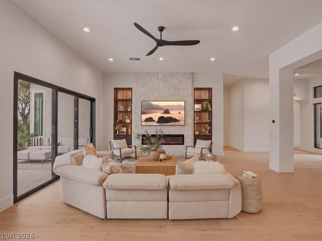 3 Isleworth Drive, Henderson, NV 89052 A refined living space showcasing a stone-clad fireplace and seamless outdoor access.