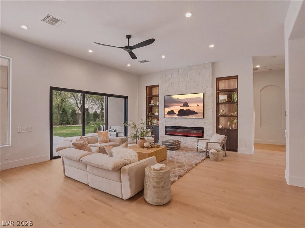 3 Isleworth Drive, Henderson, NV 89052 Blonde hardwood floors grace this living space, offering outdoor views through sliding glass doors.