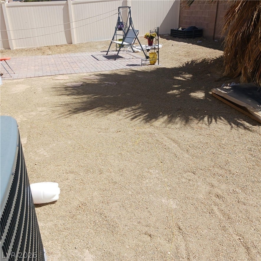 1705 Ronzard Avenue, North Las Vegas, NV 89032 An enclosed backyard features a brick paver patio area and tall vinyl privacy fencing.