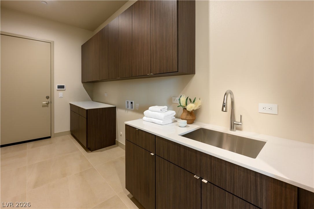Ample built-in cabinetry and a deep utility sink define this clean laundry space.