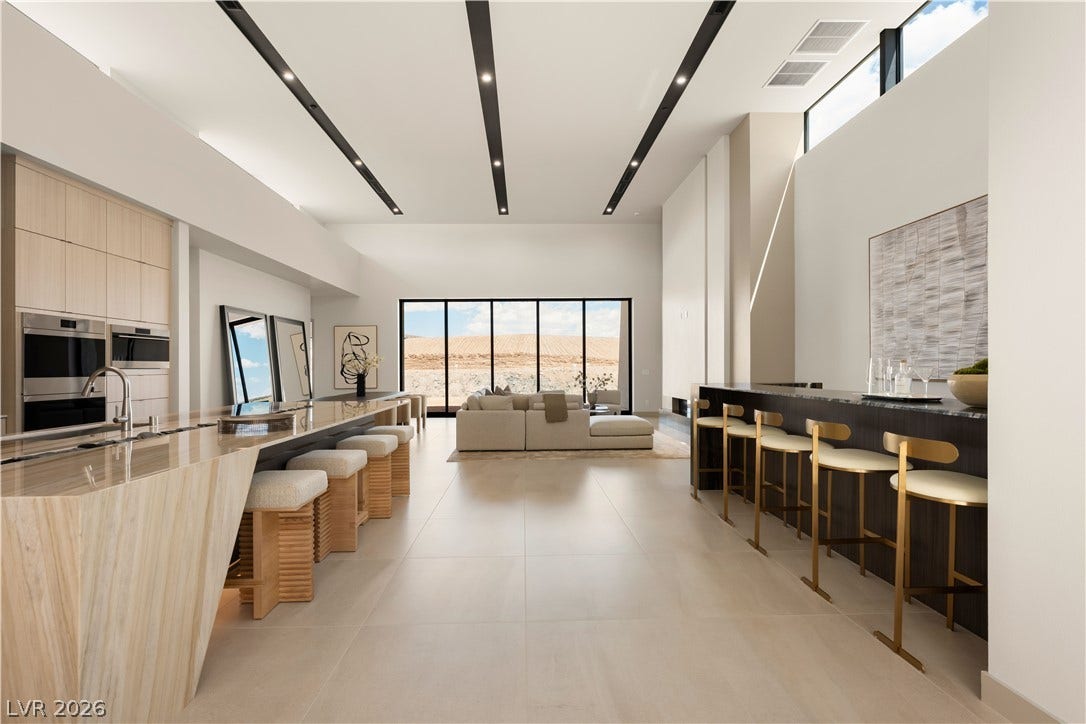 Dramatic high ceilings and matching stone-topped bars anchor this expansive open-concept living space.