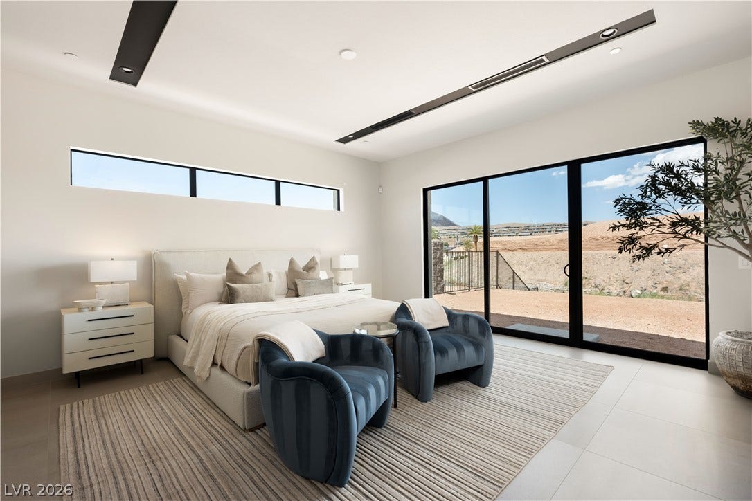 Massive sliding glass doors frame desert views in this minimalist master suite.