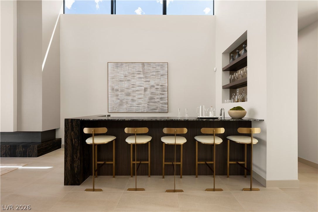 A sleek modern wet bar features natural stone counters and high ceilings with clerestory windows.