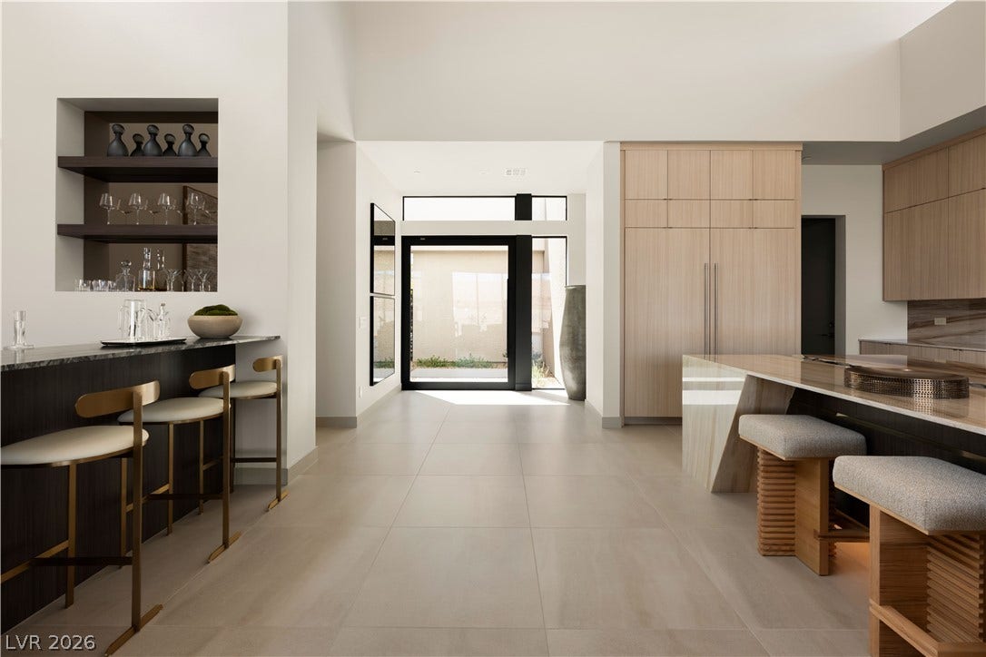 Gleaming tile floors guide the eye toward a soaring entry and custom built-in bar.