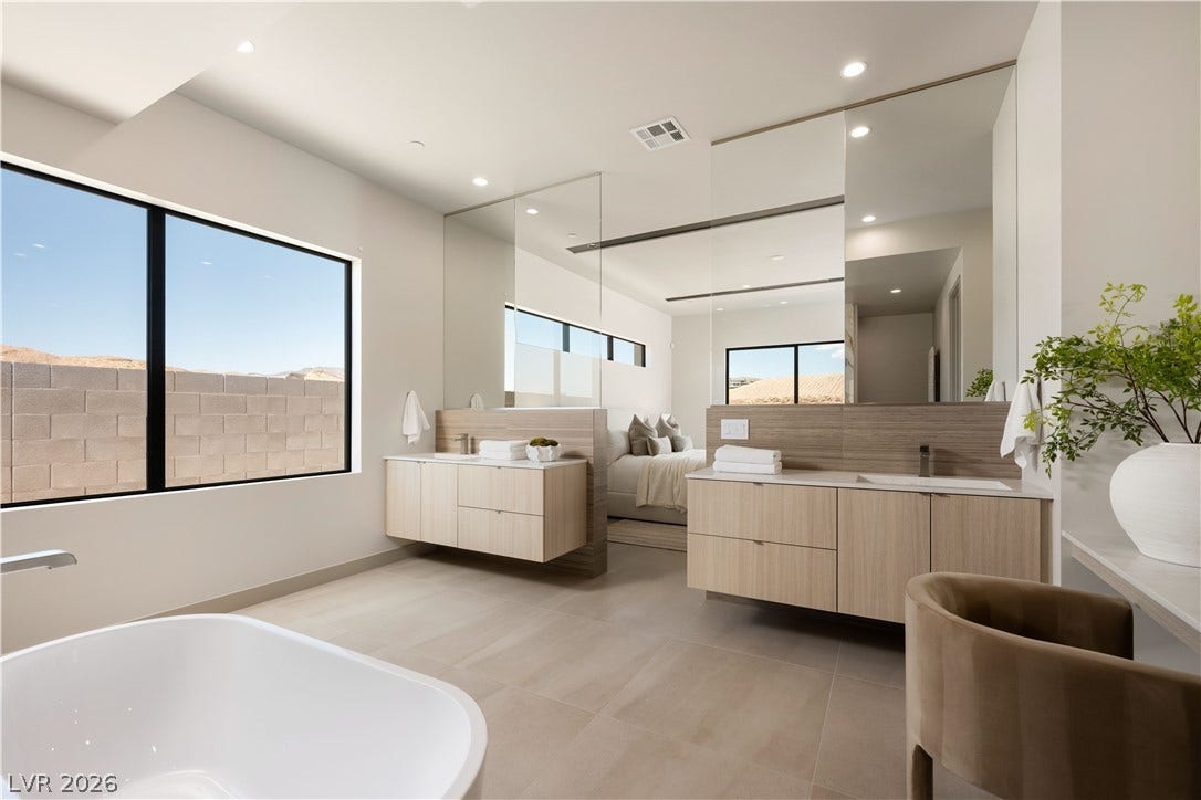 A freestanding soaking tub and dual vanities anchor this modern, light-filled primary bath.