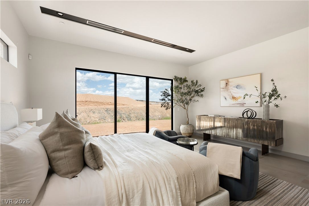 Gleaming glass sliding doors frame expansive outdoor views in this modern primary suite.