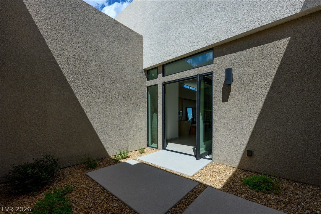 Dramatic modern geometry shapes a private entry courtyard framed by textured stucco walls.