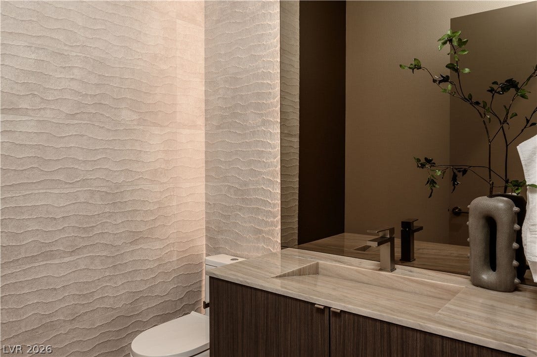 Textured wall finishes elevate the design of this modern powder room with stone vanities.