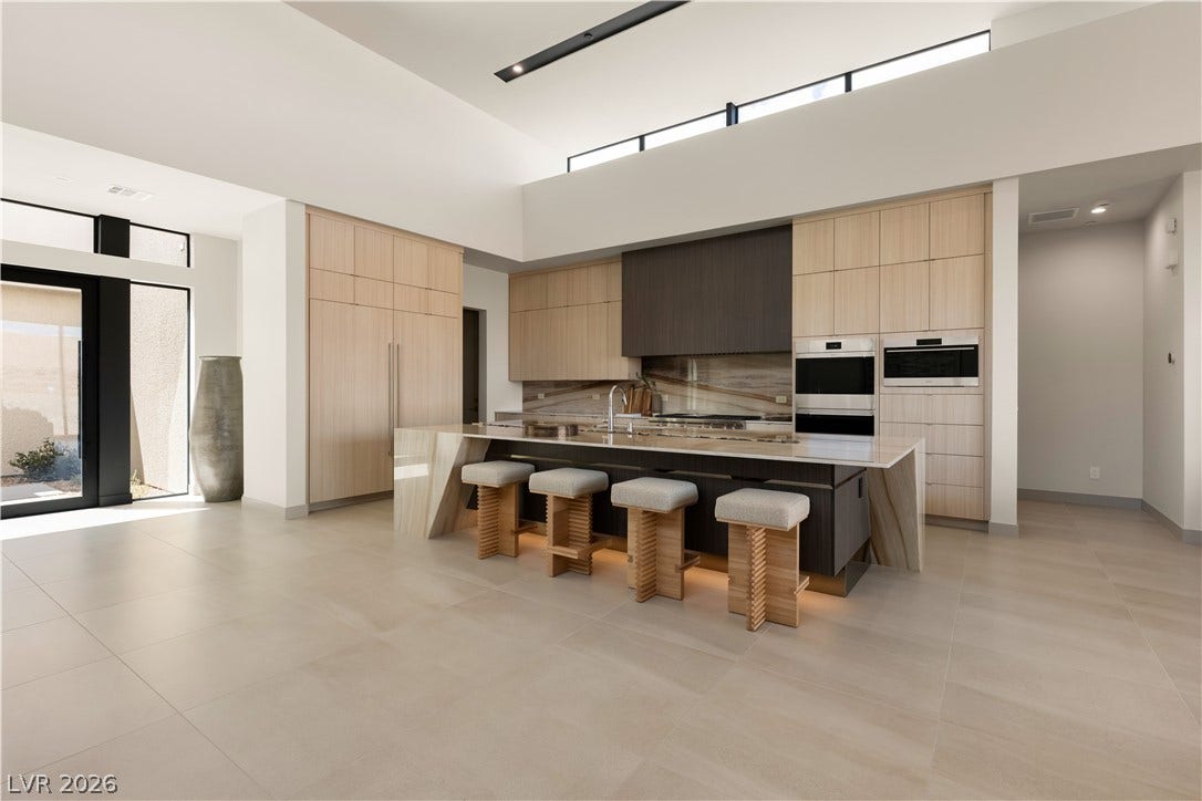 High ceilings and a stone waterfall island anchor this minimalist modern kitchen space.