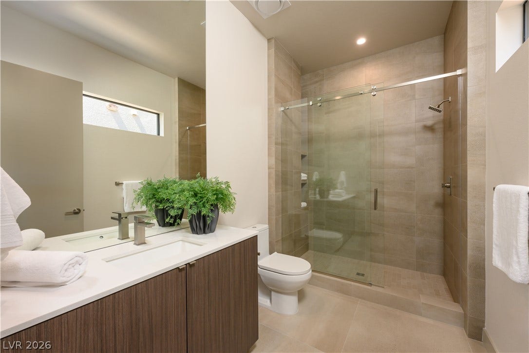 Clean lines and stone tiling define this modern bathroom with a glass-enclosed shower.