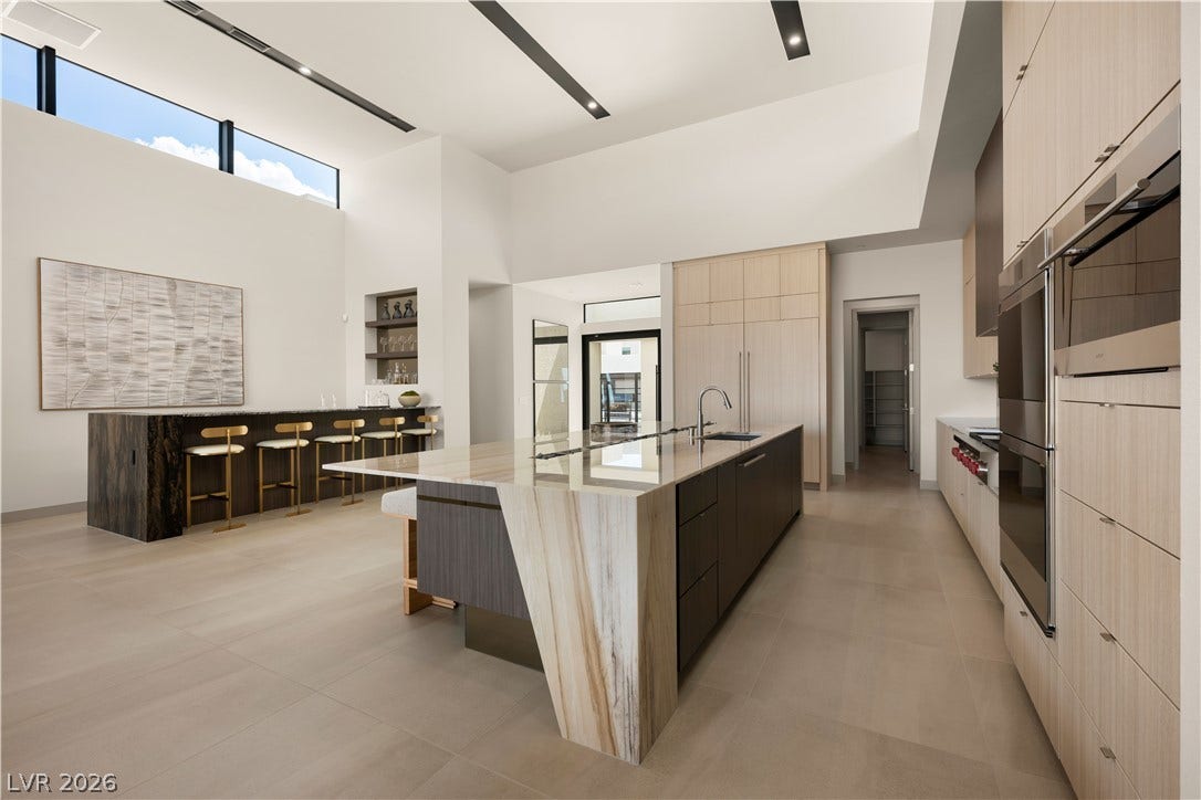 High ceilings and premium stone countertops define this architecturally striking culinary space.