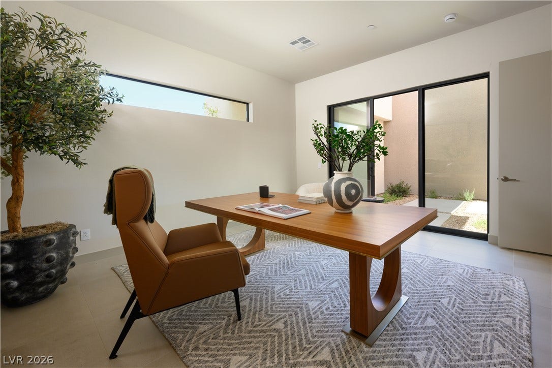 Sliding glass doors open directly to a private courtyard from this modern office workspace.