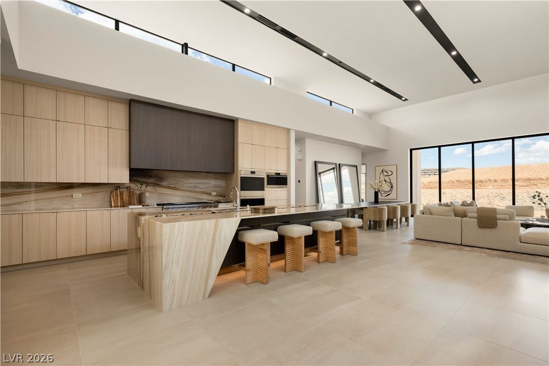 High ceilings and a stone waterfall island anchor this open-concept culinary space.