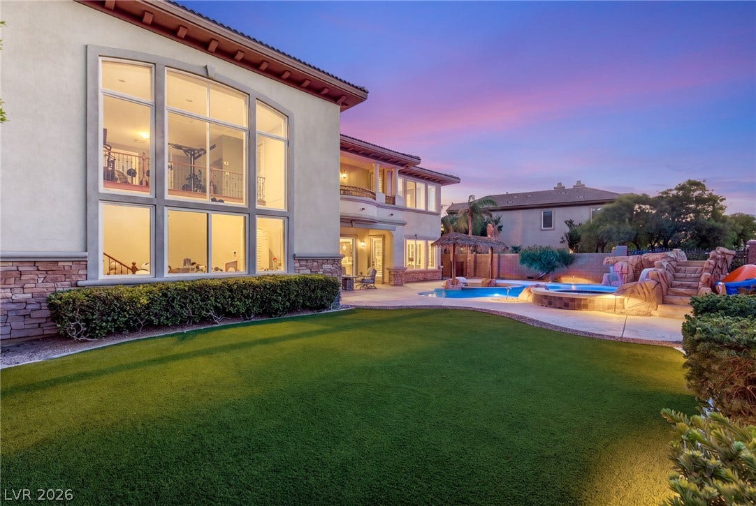 1372 Enchanted River Drive, Henderson, NV 89012 Soaring multi-tier windows overlook a manicured lawn and custom rock-scaped swimming pool.