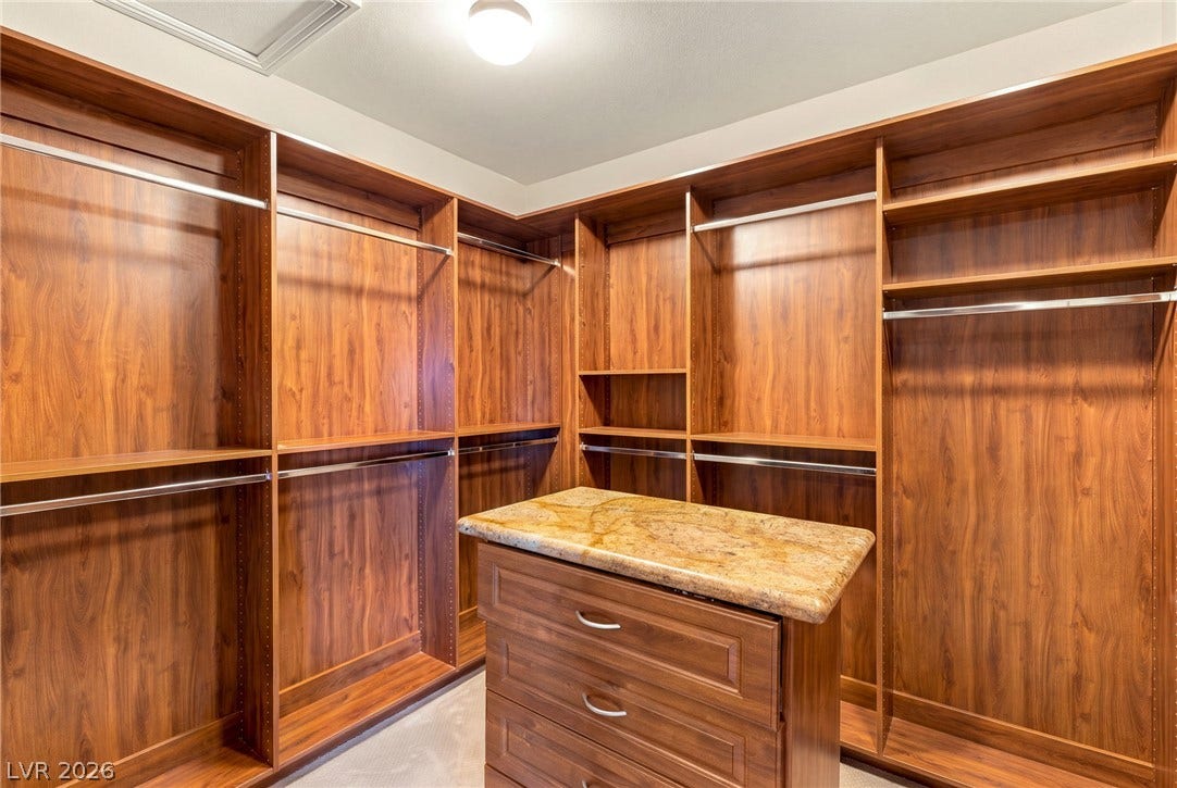 1372 Enchanted River Drive, Henderson, NV 89012 Rich wood built-ins and a stone-topped island highlight this organized wardrobe space.