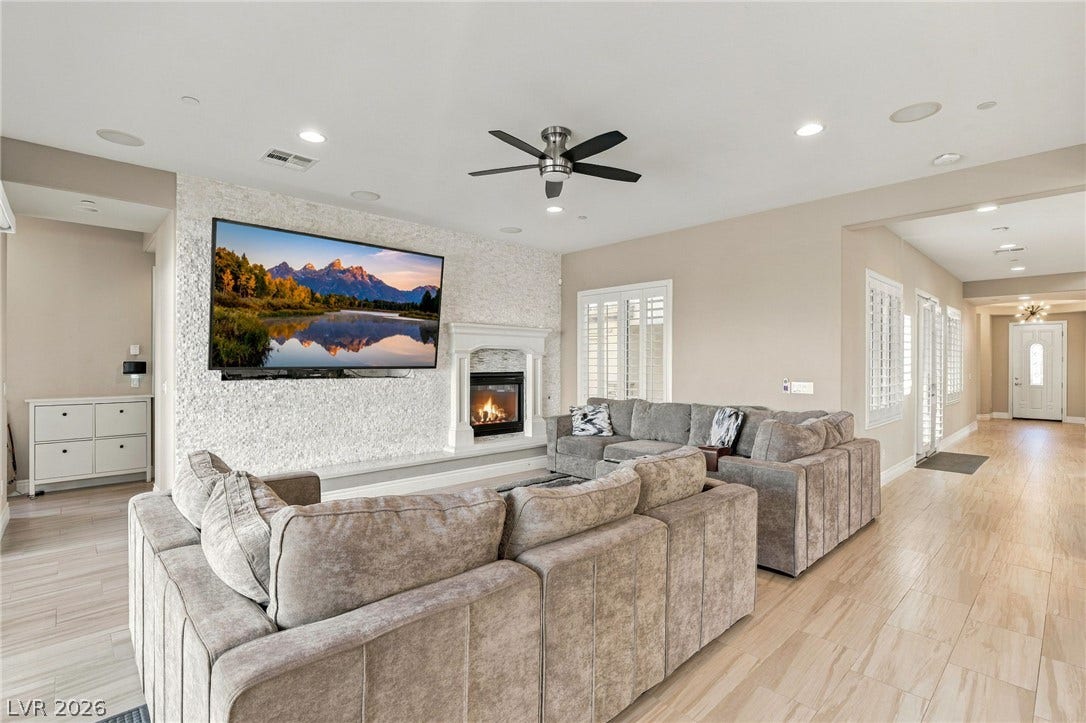 1372 Enchanted River Drive, Henderson, NV 89012 A stone fireplace wall accents this open living area with wood-look tile flooring.