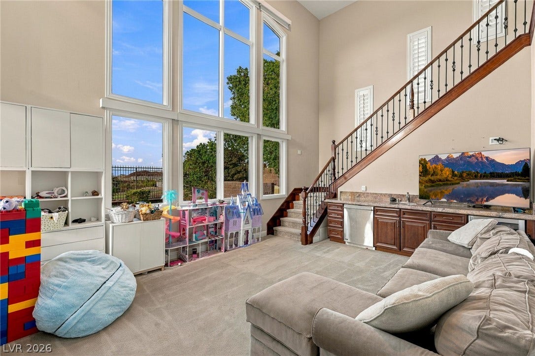 1372 Enchanted River Drive, Henderson, NV 89012 Towering windows illuminate the spacious living area featuring a custom wet bar and elegant staircase.