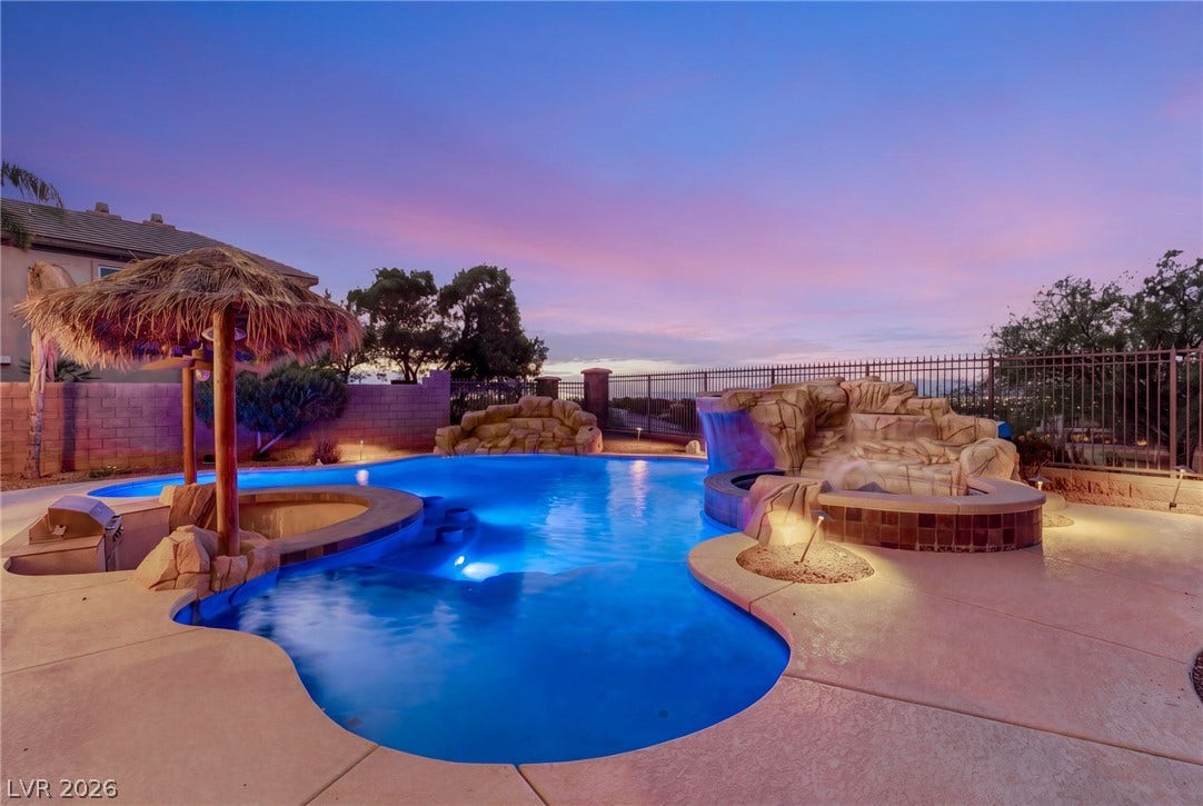 1372 Enchanted River Drive, Henderson, NV 89012 A resort-style swimming pool features custom rock waterfalls and a swim-up bar beneath a palapa.