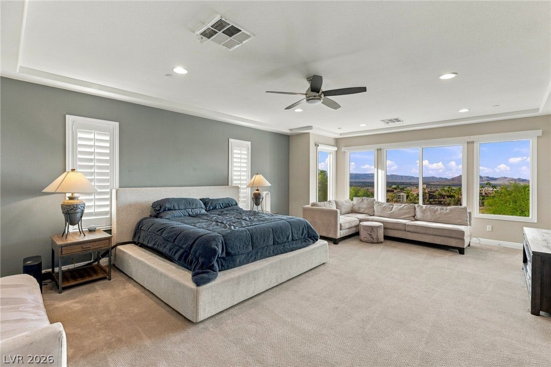 1372 Enchanted River Drive, Henderson, NV 89012 A spacious bedroom features recessed lighting, plush carpeting, and expansive windows showcasing mountain views.