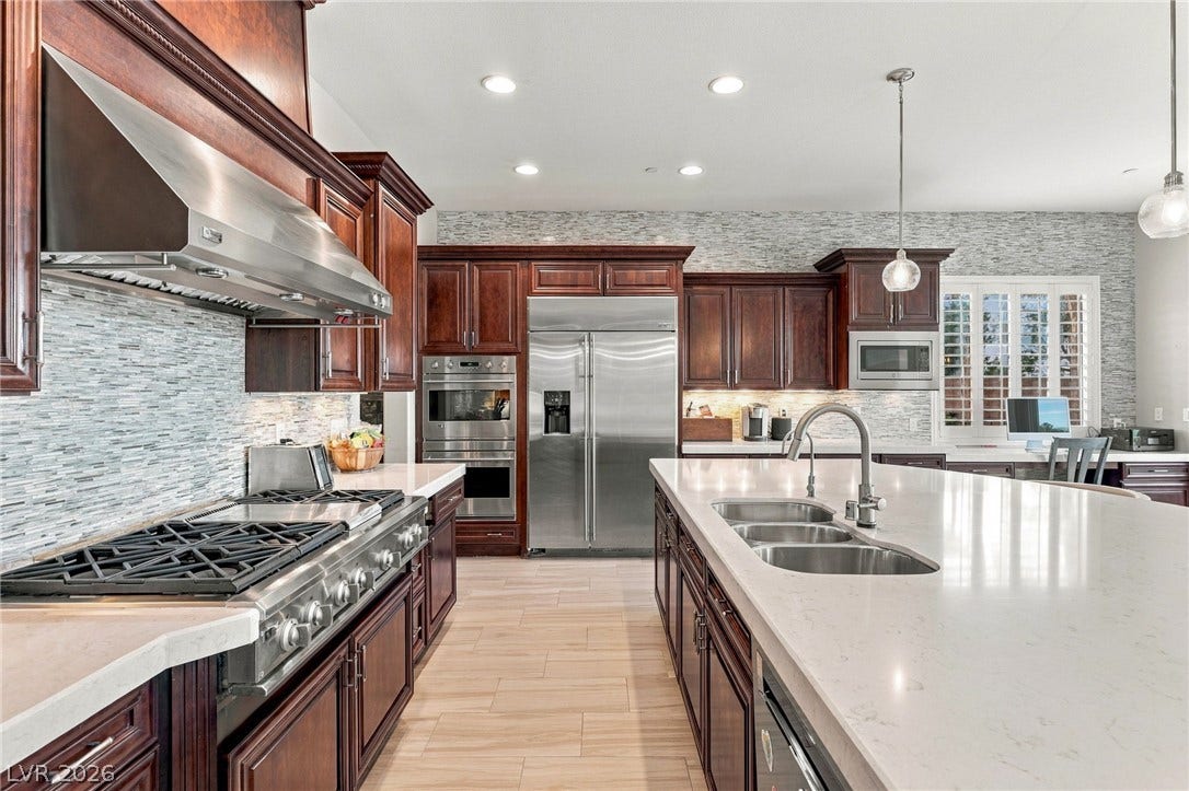 1372 Enchanted River Drive, Henderson, NV 89012 Gleaming stone counters pair with rich wood cabinetry in this culinary workspace.