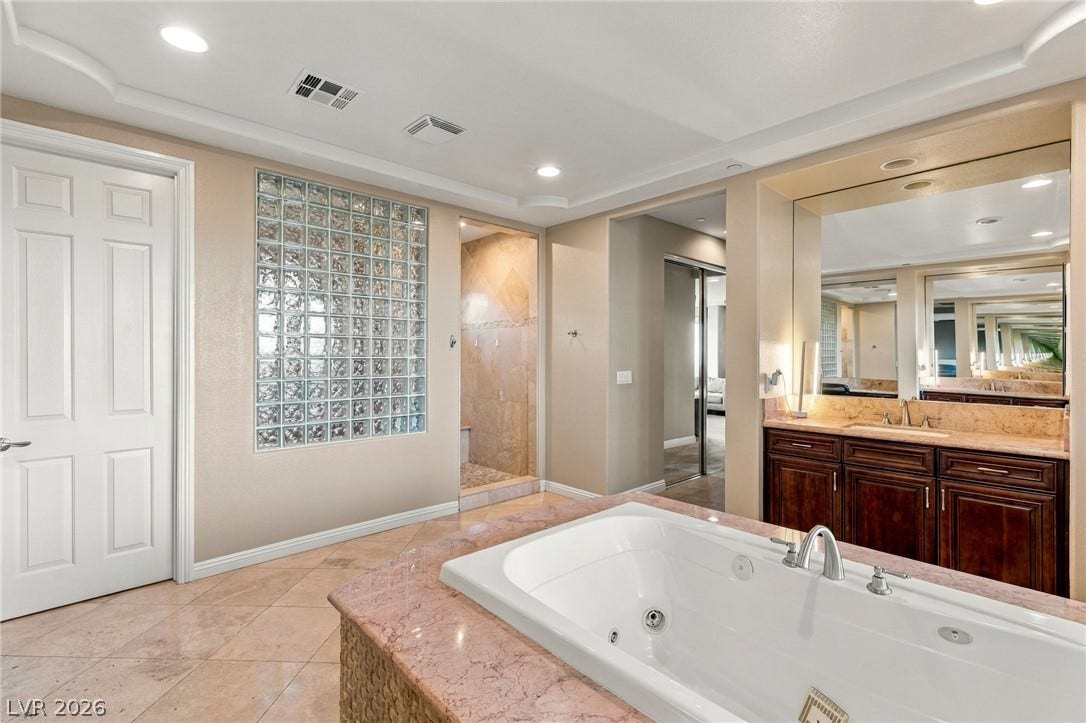 1372 Enchanted River Drive, Henderson, NV 89012 Fine tile flooring pairs with a sunken tub and rich stone counters in this bath.