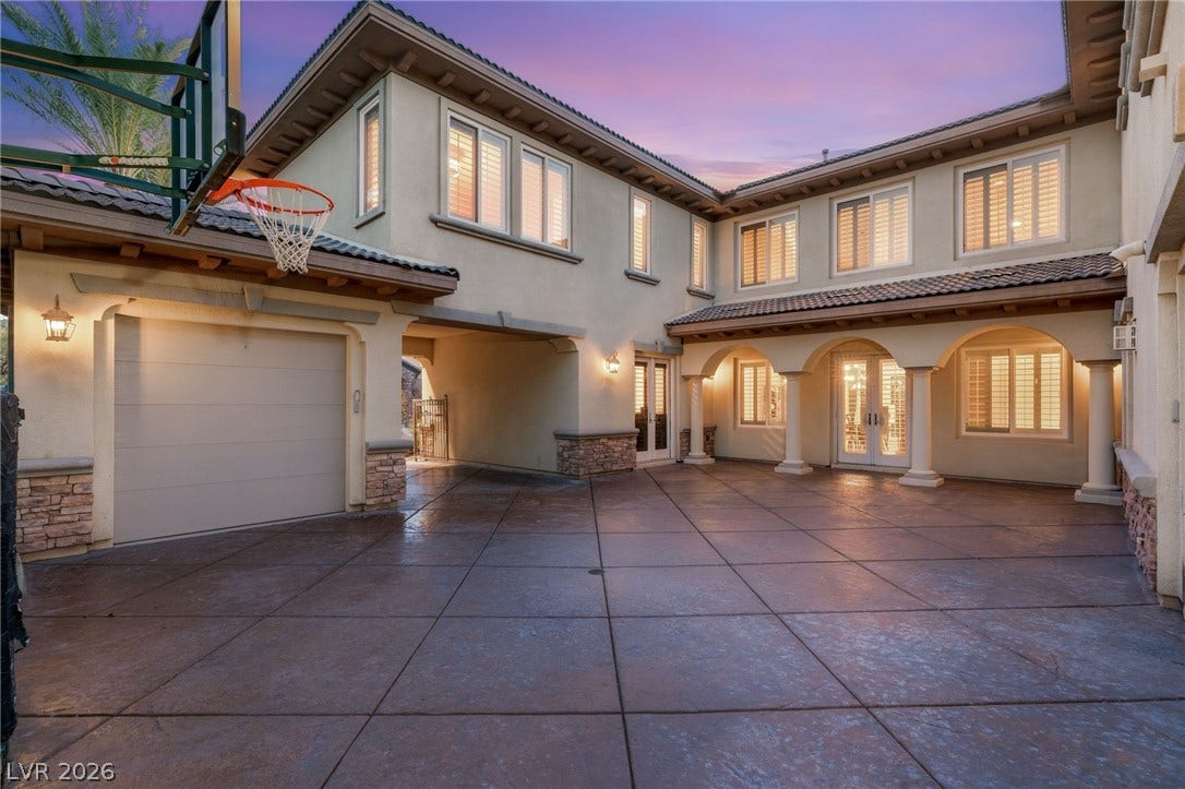 1372 Enchanted River Drive, Henderson, NV 89012 An expansive patterned concrete driveway leads to an arched portico and multi-car garage.