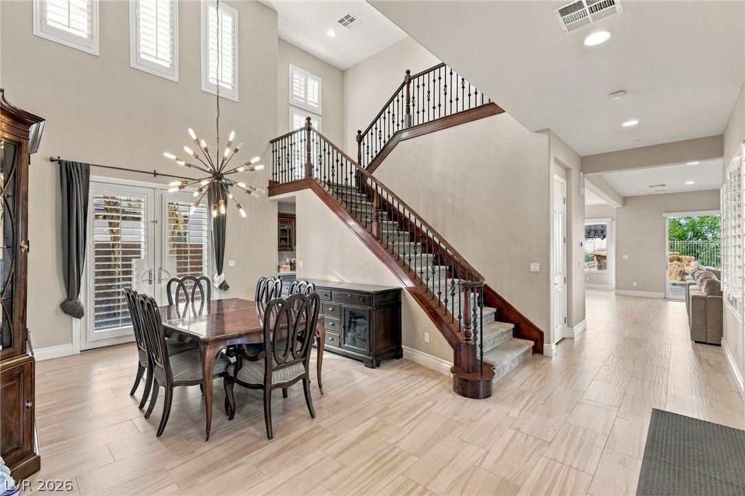 1372 Enchanted River Drive, Henderson, NV 89012 Soaring ceilings and a grand wood staircase elevate this welcoming open-concept dining space.