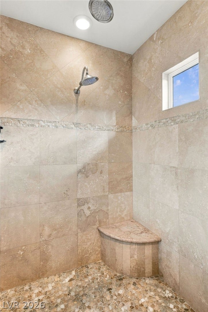 1372 Enchanted River Drive, Henderson, NV 89012 Floor-to-ceiling stone tile accents this custom walk-in shower complete with a built-in bench.