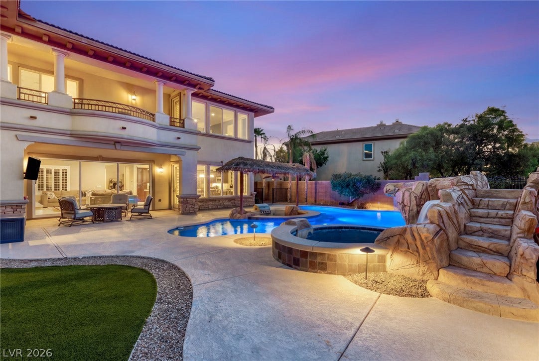 1372 Enchanted River Drive, Henderson, NV 89012 A resort-style swimming pool and custom rock waterfall slide anchor this desert backyard oasis.
