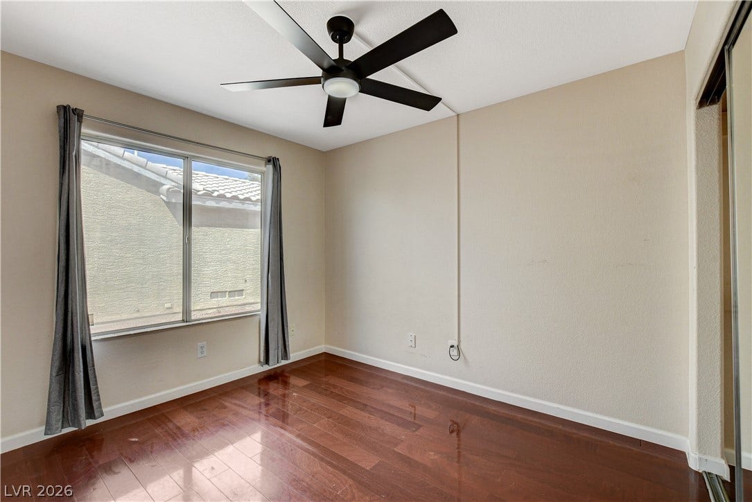 5239 Ferrell Mountain Court, North Las Vegas, NV 89031 Rich wood flooring anchors this comfortable bedroom space illuminated by a large window.