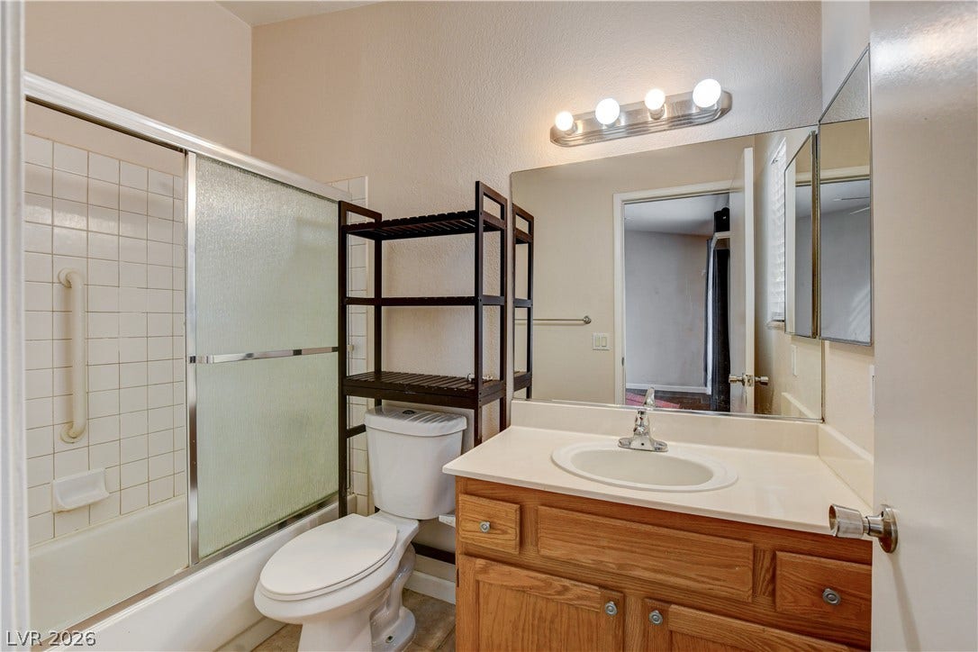 5239 Ferrell Mountain Court, North Las Vegas, NV 89031 Tiled tub enclosure sits alongside a single vanity with wood cabinetry.