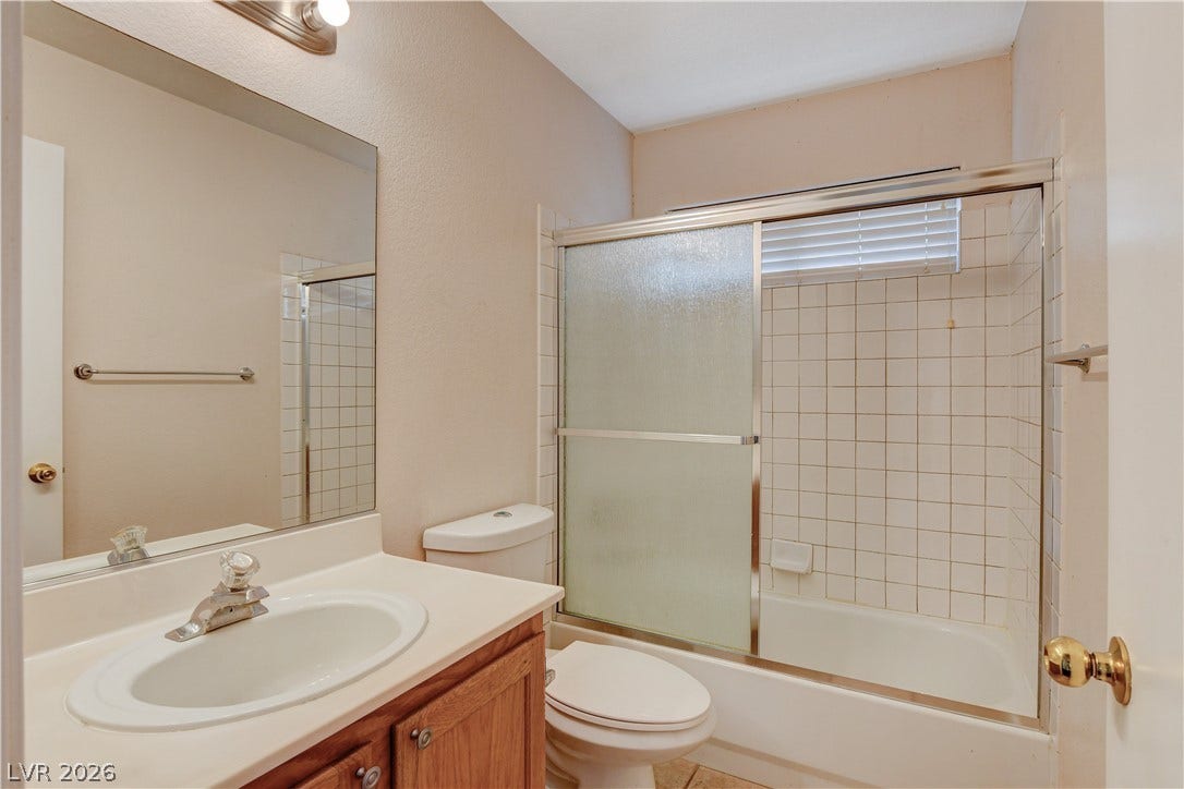 5239 Ferrell Mountain Court, North Las Vegas, NV 89031 Tiled tub and shower enclosure sits adjacent to a classic single-sink vanity.