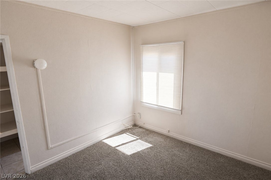 123 W Victory Road, Henderson, NV 89015 Natural light streams through a window into this cozy bedroom featuring soft carpeting.