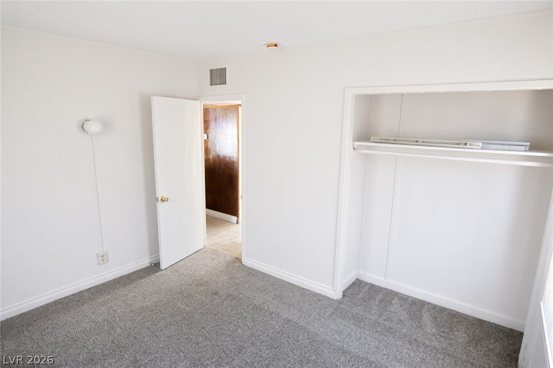 123 W Victory Road, Henderson, NV 89015 A neutral bedroom features wall-to-wall carpeting and a spacious built-in closet.