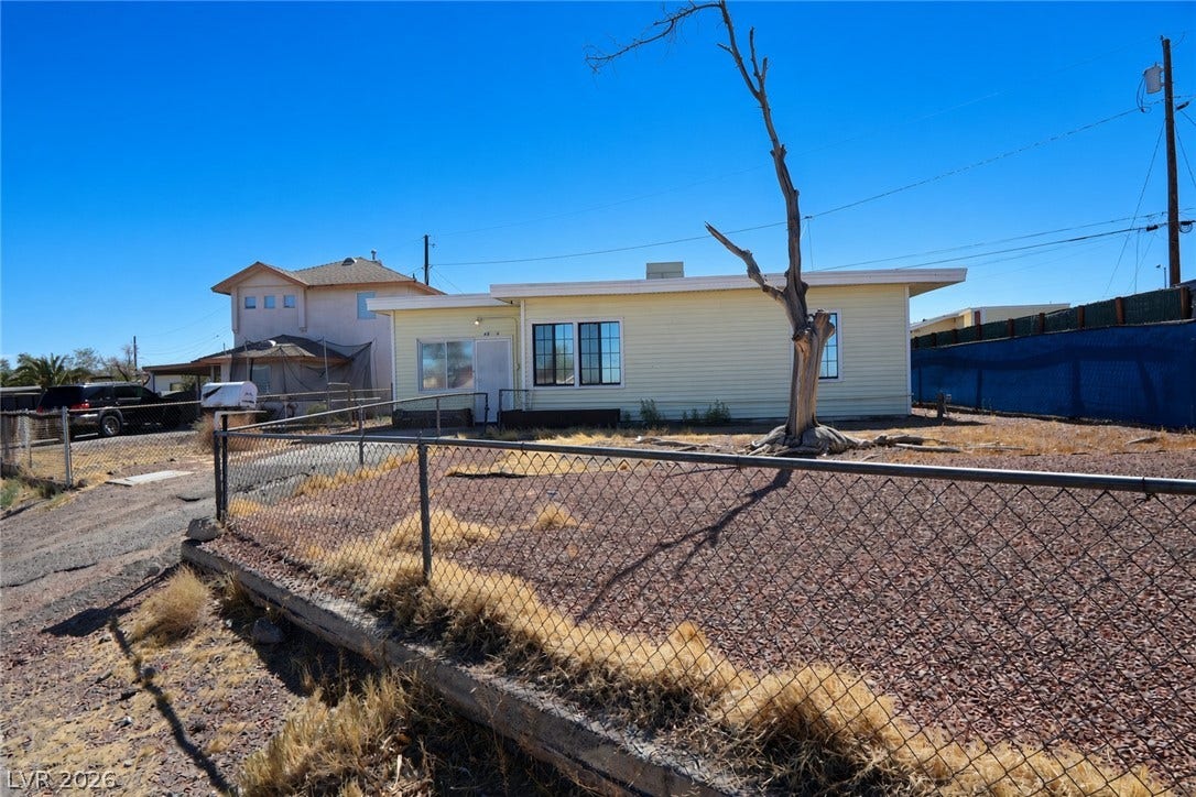 123 W Victory Road, Henderson, NV 89015 A classic single-story exterior features a low-maintenance yard enclosed by chain-link fencing under clear skies.
