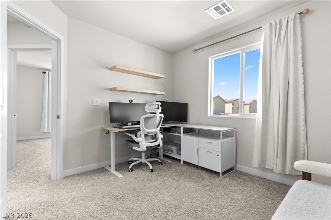 Plentiful natural light fills this versatile space finished with neutral carpeting and high ceilings.