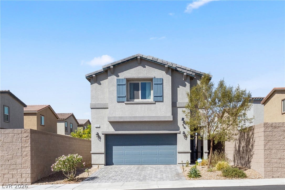 Classic stucco exterior showcases a paved driveway and decorative shutters under clear desert skies.