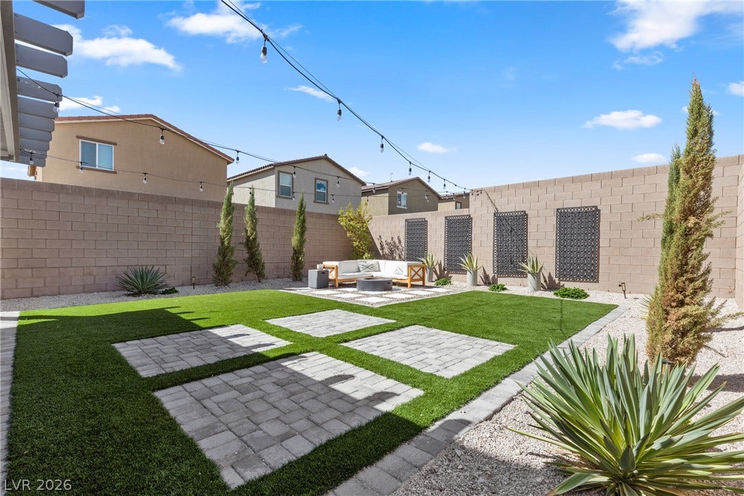 Neat stone pavers and lush synthetic turf create a beautifully structured, low-maintenance outdoor retreat.