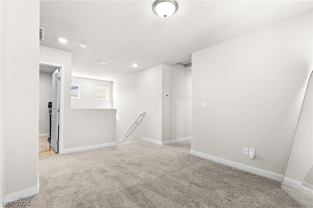 Plush carpeting and crisp white walls define this versatile upper-level landing space.