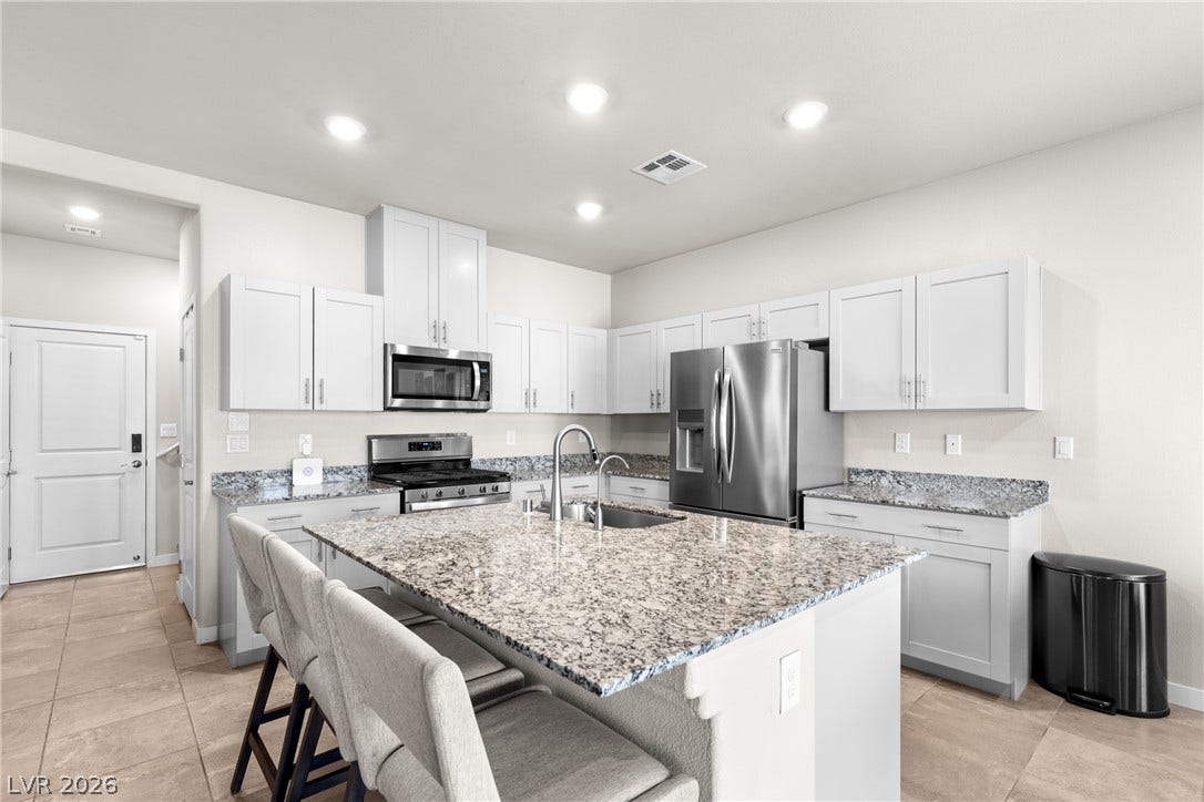 Polished granite countertops and classic shaker cabinetry anchor this open culinary workspace.
