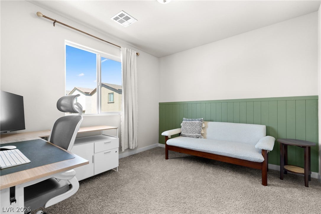 A light-filled secondary bedroom features plush carpeting and a large window overlooking the neighborhood.