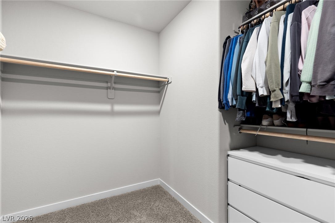 Ample hanging rods and soft carpeting define this functional walk-in closet space.