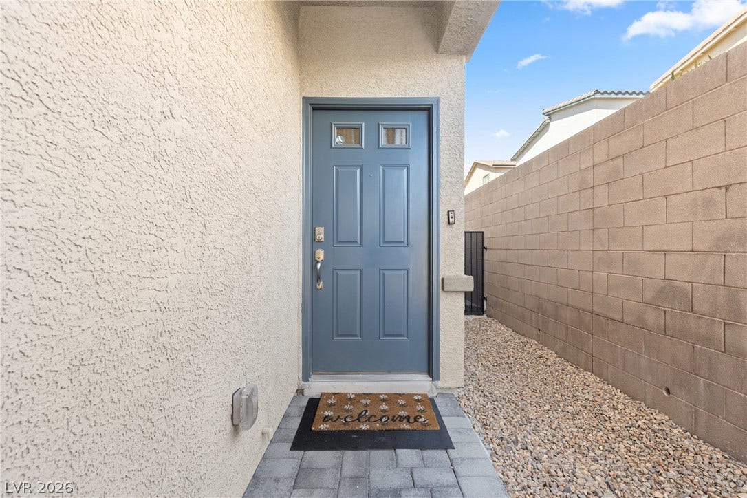 An inviting entryway features a classic paneled front door set against durable stucco siding.