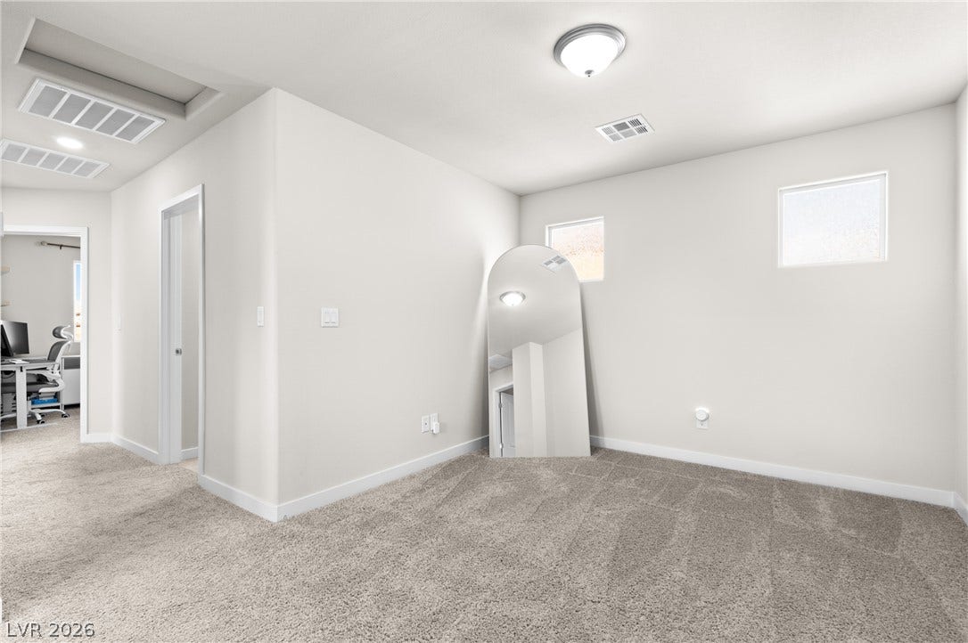 High windows invite natural light into this versatile carpeted space.