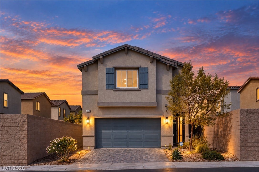 An inviting two-story stucco exterior showcases structured block walls and a paved driveway under vibrant skies.
