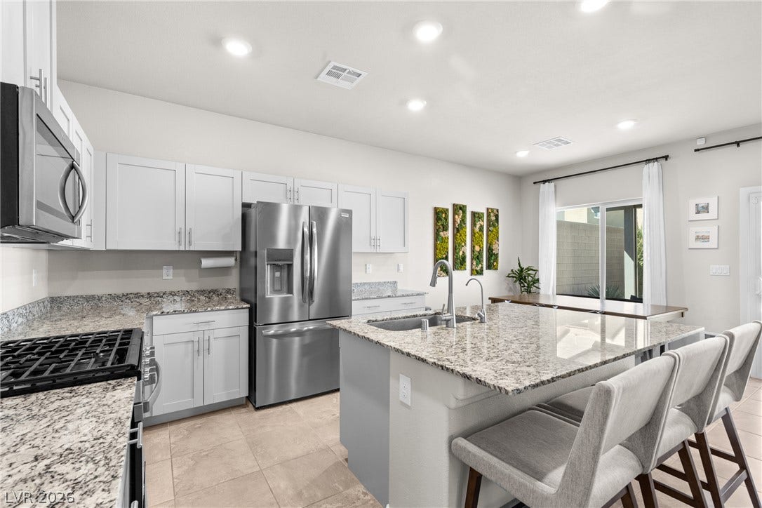 Polished granite countertops and classic shaker cabinetry anchor this light-filled modern kitchen.